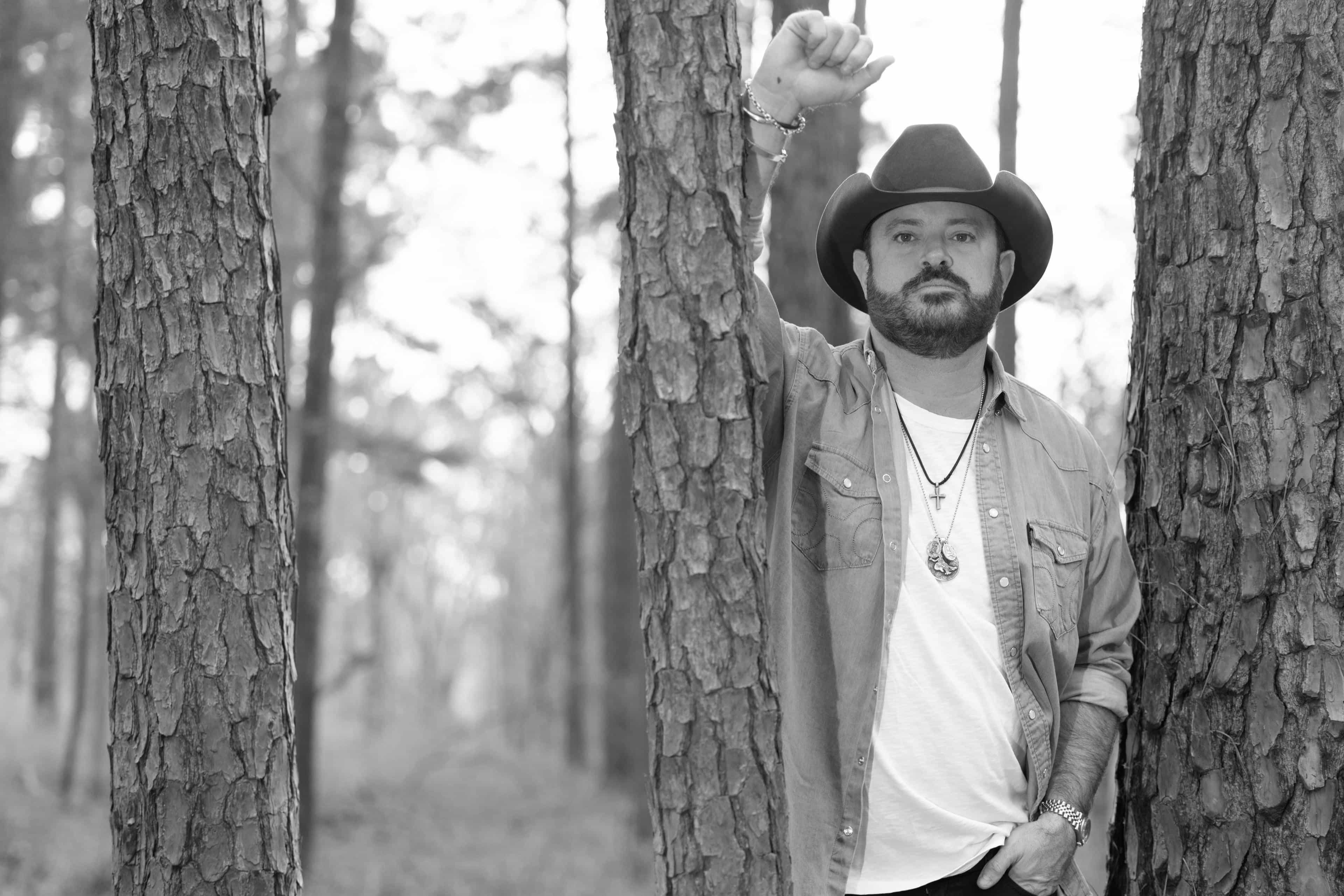 Black and white photo of Wade leaning against a tree